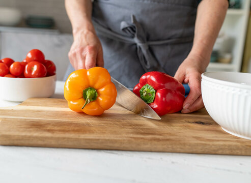 Woman preparing bell peppers on a cutting board in the kitchen