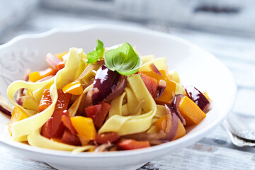 Pappardelle Pasta with Vegetables and fresh Basil and Ham on bright wooden Background. Close up.	