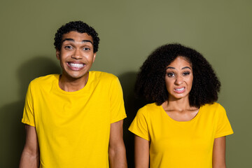 Photo of two young people grinning teeth wear t-shirt isolated on khaki color background