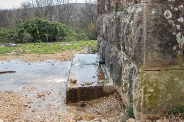 Old stone well, water gushes out - obrazy, fototapety, plakaty