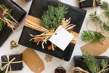Black Christmas present with blank gift tag, with fir branch and decorations, Mockup