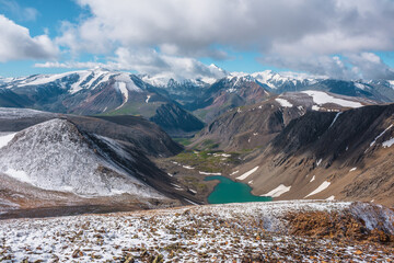 Scenic view from above to most beautiful turquoise alpine lake among hills in freshly fallen snow...