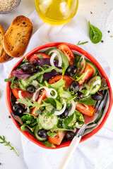 Fresh organic salad with tomatoes, cucumber, olives and greens. Healthy diet vegan food, Mediterranean vegetable greek salad on white kitchen table copy space