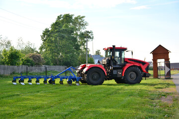 a red tractor with plow isolated on green lawn