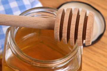 Cuillère à miel en bois posée sur un pot de miel