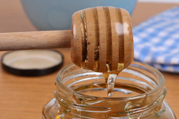 Miel liquide coulant d'une cuillère à miel en bois dans un pot de miel