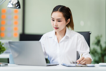 In the office, a businesswoman, accountant by profession, works on financial documents. She uses a computer to calculate income, analyze data, and manage budgets. Asian people.