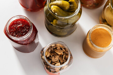 food, eating and preserve concept - close up of jars with preserves on white background