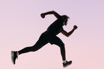 Athletic sprinter jumping mid air in a studio silhouette, training with determination - 782143514