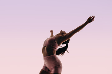Fit ballerina displaying athletic movement in a studio silhouette - obrazy, fototapety, plakaty