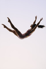 In-flight gymnast: A female acrobatics performer leaps mid-air in a graceful routine - 782143551