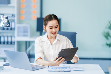In the office, a businesswoman, accountant by profession, works on financial documents. She uses a computer to calculate income, analyze data, and manage budgets. Asian people.