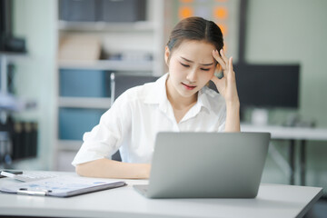 Asian people, In the corporate office, a young businesswoman sits at her desk, feeling exhausted...