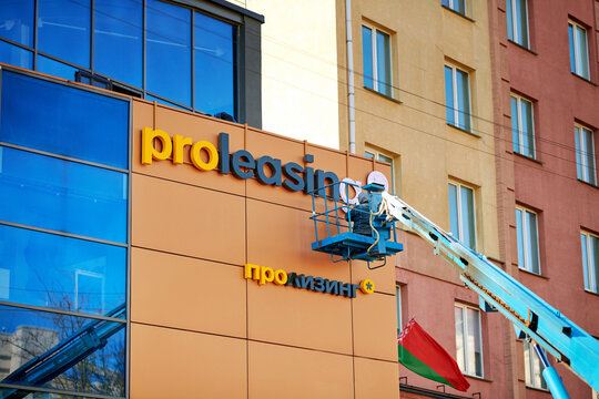 Minsk, Belarus. Mar 2, 2024. Worker on mobile crane install PROleasing advert on facade of modern building. Worker on aerial platform, facade works..