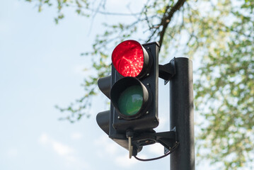 Close-up of red traffic light for cars with a blue sky in the background.