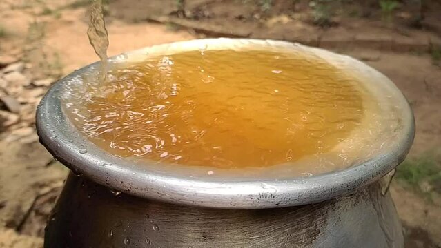 Bad, dirty, contaminated, impure, unhealthy, unhygienic, muddy and rusty brown colour drinking tap water overflowing from pot. Water shortage, scarcity crisis in india and africa rural village concept