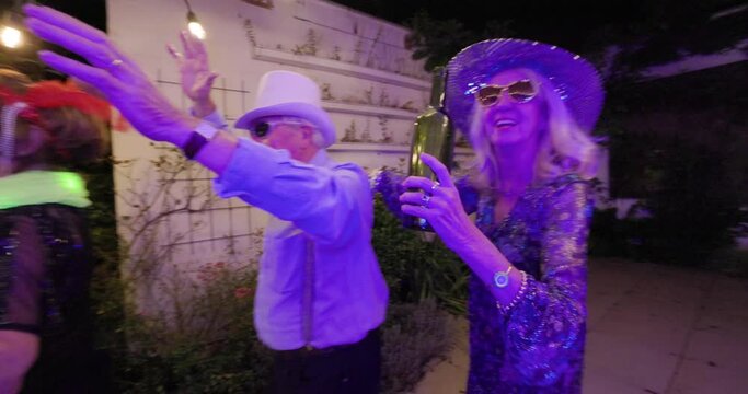 This lively video showcases a group of spirited senior guests enjoying a dance at an outdoor party. With a cheerful ambiance, they move rhythmically to the music, showcasing a conga line, toasts, and
