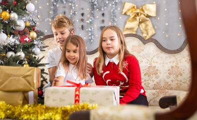 Fototapeta na wymiar Two girls and boy on sofa in Christmas interior