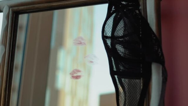 sexy girl writes a love message on the mirror and glass with red lipstick. The phrase I love you on the first date of a man and a woman. Erotic and romantic atmosphere with hearts and black lace bra