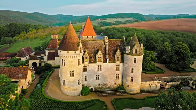 Cinematic stained glass castle with mullioned windows and rooms opening into the valley in France. Aerial view of Fortress at golden sunset in France,