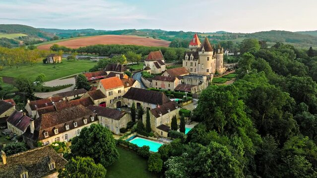 Cinematic stained glass castle with mullioned windows and rooms opening into the valley in France. Aerial view of Château des Milandes fortress at golden sunset in France,