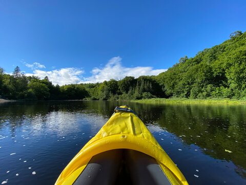Yellow kayak on the lake. Inflatable kayak on a peaceful river in summer. Point a canoe surrounded by water, mountains and trees. Paddle on calm seas.