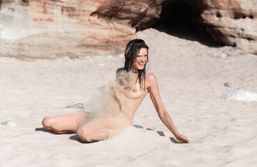 Young woman posing nude on a sandy beach