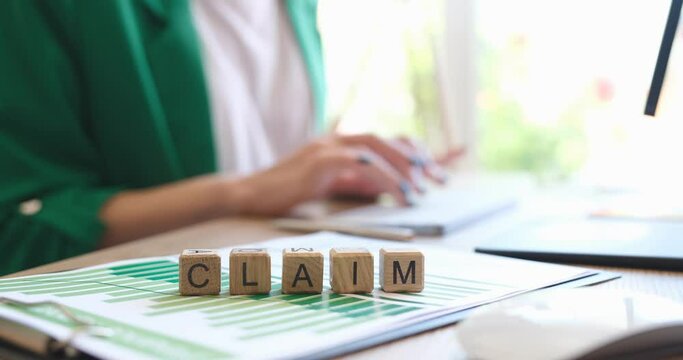 Businesswoman typing on keyboard against background of wooden cubes with word claim 4k movie. Claim insurance compensation concept