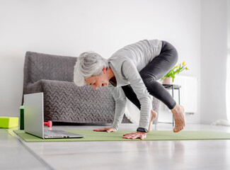 Pleasant 70-Year-Old Woman Performs Complex Exercises With Trainer Through Laptop, Doing Yoga...