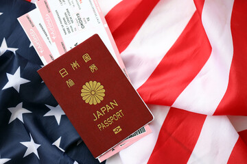 Japan passport with airline tickets on American US flag close up. Tourism and travel concept