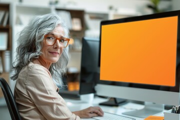 Fototapeta na wymiar App mockup shoulder view of a middle-aged woman in front of a computer with a fully orange screen