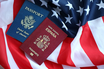 Passport of Spain with US Passport on United States of America folded flag close up