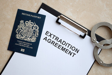 Passport of Great Britain and Extradition Agreement with handcuffs on table close up