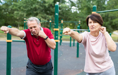 Sports pensioners are engaged in martial art on the sports ground in open air
