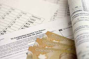 Canadian T2 tax form Corporation income tax return lies on table with canadian money bills close...