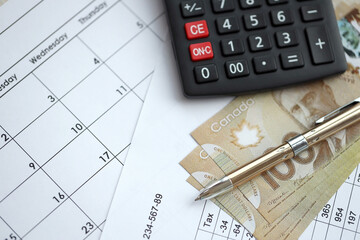 Naklejka premium Many calculation results in schedules lies on table with canadian money bills, calculator and pen close up. Taxation and annual accountant paperwork in Canada