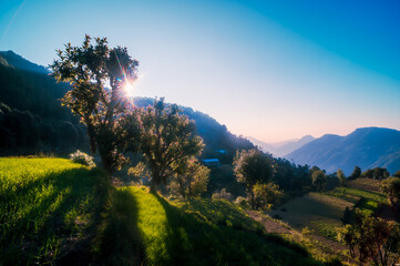 Landscape with sun rays. Serene peaceful view of Himalayan mountains in the  Kumaun region village. Showing hues at dusk sunrise with sun rays passing between mountains. Uttarakhand, India.