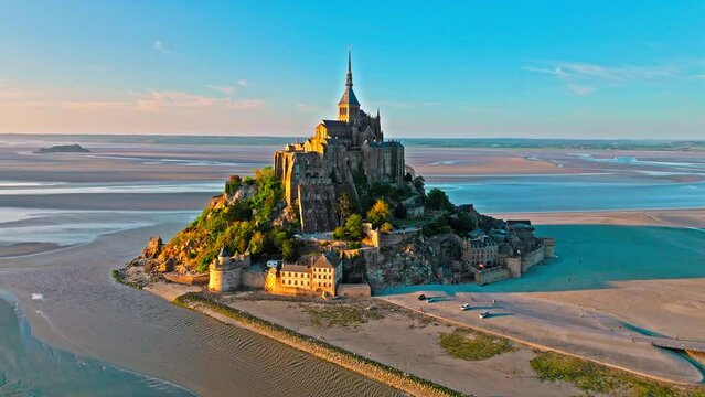 Aerial dramatic sunset over iconic French castle in Europe. Mont Saint-Michel on a tidal island in Normandy, France.