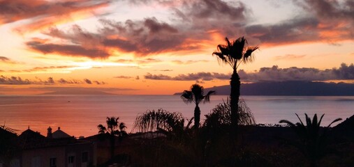 breathtaking sunset in Tenerife in the Canary Islands, overlooking the palm trees, the ocean and the opposite island of Gomera.
