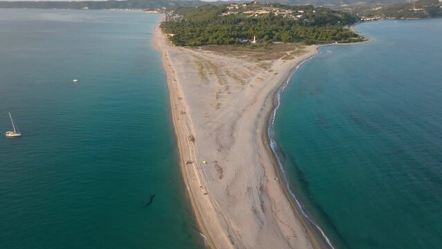 A drone flying backwards captures Cape Possidi, Halkidiki, Greece, with a sandy beach and clear blue waters