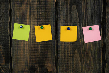 Blank notepaper and space for text with push pins on wooden background. note blank color paper cards on wooden board. noticeboard. blanks for designers