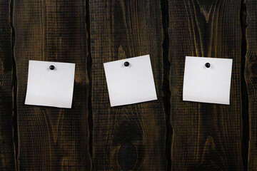 White blank notepaper and space for text with push pins on wooden background. note blank color paper cards on wooden board. noticeboard. blanks for designers