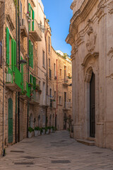 Fototapeta na wymiar Centro storico di Molfetta. Piccola strada acciottolata ed edifici residenziali in pietra. Puglia, Italia.