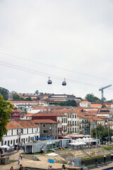 Fototapeta na wymiar Two gondolas with tourists from the Gaia cable car passing just above the Vila Nova de Gaia neighborhood, port and restaurants full of strolling tourists. Port. Portugal.