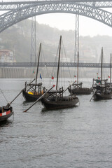 Wooden rabelos boats docked in the Douro River in Oporto, with barrels of wine, with the Don Luis I...