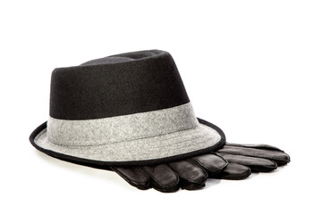 A mans black fedora hat with a white band with black leather gloves isolated on white