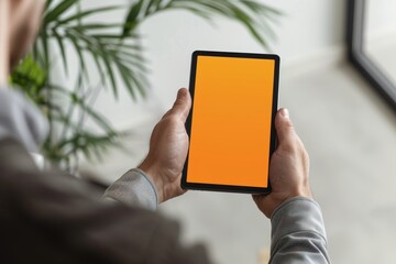 App mockup shoulder view of a adult man holding an ebook with a completely orange screen