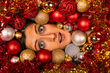 Young woman face surrounded by Christmas's balls.