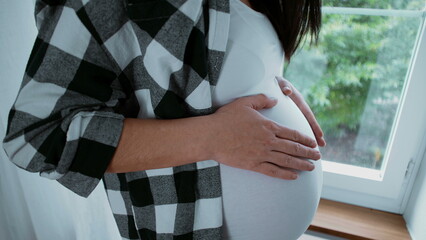 Beautiful maternal moment of expectant mother caressing her 8 month belly awaiting with...