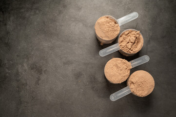 Chocolate protein powder in scoops. Food supplement, nutrition. Copy space 